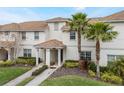 Inviting townhome featuring stucco walls, a tile roof, well-manicured lawn and mature palm trees at 9043 Dogleg Dr, Davenport, FL 33896