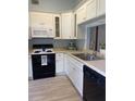 White kitchen with black appliances and light grey tile floors at 89 Crooked Pine Rd, Port Orange, FL 32128