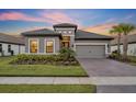 Charming single-story home with a tile roof, paver driveway, well-manicured lawn, and lush landscaping at dusk at 1511 Goblet Cove St, Kissimmee, FL 34746