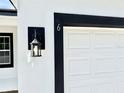 White garage door with black frame and exterior light at 6 Malauka Pass, Ocklawaha, FL 32179