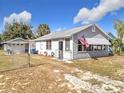 Gray house with American flag and detached garage, surrounded by a yard at 1119 Pine Ave, Tavares, FL 32778