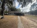 Home's backyard with a stone pathway leading to a covered patio area at 5690 Sw 202Nd Ct, Dunnellon, FL 34431