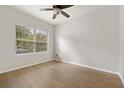 Bright, minimalist bedroom featuring wood-look flooring, a ceiling fan and a window with tree views at 7525 Azalea Cove Cir, Orlando, FL 32807