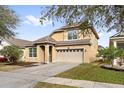 Two-story house with tan exterior, two-car garage, and landscaping at 7525 Azalea Cove Cir, Orlando, FL 32807