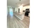 Modern kitchen with island, stainless steel appliances, and wood-look tile floors at 9884 Red Eagle Dr, Orlando, FL 32825