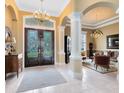 Elegant foyer featuring double doors, tile flooring, decorative columns, and a grand chandelier at 103 Arrowhead Ct, Winter Springs, FL 32708