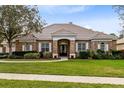 Charming brick home with manicured lawn, tile roof, and a double-door entry with decorative glass at 103 Arrowhead Ct, Winter Springs, FL 32708