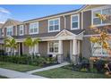 Townhome with light brown siding, a beige door, and palm trees at 11574 Buoy Point Pl, Orlando, FL 32832