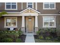 Front entrance of townhome, featuring a beige door and stone pillars at 11574 Buoy Point Pl, Orlando, FL 32832