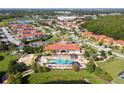 Aerial view of a large community pool surrounded by palm trees, sun loungers, and a well maintained club house at 1230 Las Fuentes Dr, Kissimmee, FL 34746