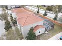 Aerial view of a home with a screened-in pool area and a red tile roof and well manicured lawn at 1230 Las Fuentes Dr, Kissimmee, FL 34746
