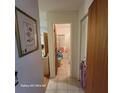 Hallway with tile flooring leading to a bathroom, with a closet and a rose-themed painting on the wall at 1420 Thousand Roses S Dr, Lake Wales, FL 33853