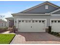 Two car garage with white doors and brick paver driveway at 17597 Summersweet Way, Clermont, FL 34714