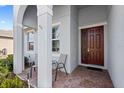 Brick paved porch with two chairs and a burgundy front door at 3999 Night Heron Dr, Sanford, FL 32773