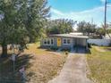 Ranch-style home with gray exterior, yellow door, and driveway at 4400 Southmore Dr, Orlando, FL 32812