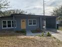 Gray house with yellow door and carport, showcasing curb appeal at 4400 Southmore Dr, Orlando, FL 32812