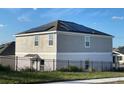 Rear view of house showing solar panels on the roof and a fenced backyard at 768 Staffora St, Haines City, FL 33844