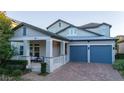 Two-story house with gray siding, two-car garage, and a stone-accented front porch at 14746 Scott Key Dr, Winter Garden, FL 34787