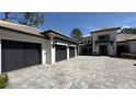 Modern home showcasing a spacious three-car garage with an expansive paver driveway at 16902 Vinci Way, Montverde, FL 34756