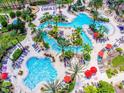 A stunning aerial view of the resort-style pool featuring a lazy river, multiple pools, and lush tropical landscaping at 3632 Calabria Ave, Davenport, FL 33897