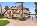 Two-story house with tile roof, landscaping, and a gated driveway leading to lake at 10018 Lone Tree Ln, Orlando, FL 32836