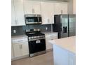 Well-lit kitchen featuring modern appliances, sleek cabinets, and a stylish backsplash at 520 Orient Ave, Debary, FL 32713