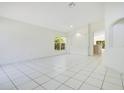 Bright living room with white tile flooring, neutral walls, and an arched doorway leading to the kitchen at 441 Tree Shore Dr, Orlando, FL 32825