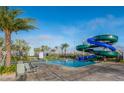 Community splash pool with water slides surrounded by lounge chairs and palm trees at 4731 Clock Tower Dr # 401, Kissimmee, FL 34746