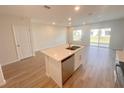 Well-lit kitchen featuring a center island with stainless steel dishwasher, white cabinetry, and wood-look tile floors at 5108 Rain Shadow Dr, St Cloud, FL 34772