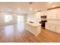Bright, modern kitchen featuring white cabinetry, stainless steel appliances, a center island, and wood-look tile floors at 5108 Rain Shadow Dr, St Cloud, FL 34772