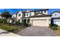 Two-story house with beige siding, solar panels, and a brick driveway at 7613 Wandering Way, Orlando, FL 32836