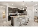 Modern kitchen with dark cabinetry, granite countertops, and an island with seating at 1366 Lava Tree Dr, Davenport, FL 33897