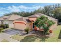 Single-story house with peach walls and red roof, nestled amongst other homes at 15938 Green Cove Blvd, Clermont, FL 34714