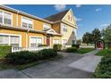 Beautiful yellow two-story townhome featuring well-maintained landscaping and a red door at 2622 Lodi Cir # 103, Kissimmee, FL 34746