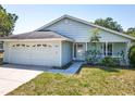 Inviting single-story home featuring light blue siding, a well-kept lawn, and an attached garage at 511 Coventry Ct, Mount Dora, FL 32757