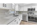 Well-lit kitchen with stainless steel appliances, gray backsplash, and white countertops and cabinets for a modern, clean design at 5300 Lido St, Orlando, FL 32807