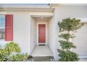 Red front door entry with red shutters and lush landscaping at 283 Archer Way, Haines City, FL 33844