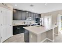 Modern kitchen with stainless steel appliances, dark cabinetry, and a large island at 445 Kestrel Dr, Groveland, FL 34736