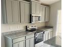 Gray cabinets, granite countertops and stainless steel appliances in a modern kitchen at 4450 Sagefield Dr, Harmony, FL 34773