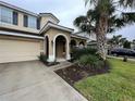 Two-story house with tan exterior, arched entryway, and palm trees at 5298 Wildwood Way, Davenport, FL 33837