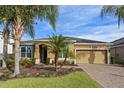 Tan one-story house with two-car garage, landscaping, and palm trees at 2158 Stillwood Way, St Cloud, FL 34771