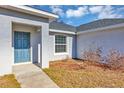 Front entry of a house with a blue door and small landscaping at 43 Water Track Dr, Ocala, FL 34472