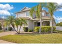 Inviting two-story home with manicured lawn, brick driveway, archway entrance and tropical palm trees at 4455 Indigo Sky Ln, Kissimmee, FL 34744
