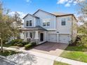 Two-story light blue house with gray accents, two-car garage, and landscaped yard at 15233 Night Heron Dr, Winter Garden, FL 34787