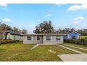 Inviting single-story house featuring a neatly kept front lawn and a light-colored facade with white window accents at 451 Rogers St, Orlando, FL 32811