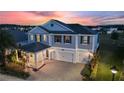 Stunning two-story home featuring a three-car garage, lush landscaping, and elegant architectural details, beautifully lit at dusk at 4608 Egg Harbor Dr, Kissimmee, FL 34746