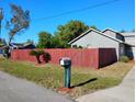 Home featuring lush green lawn, healthy shade trees, and mature red wooden fence at 1886 Elkcam Blvd, Deltona, FL 32725