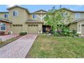 Tan two-story townhome with two-car garage and landscaped front yard at 2311 Chatham Place Dr, Orlando, FL 32824
