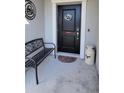 Inviting front entry with a black door and metal bench at 648 Daring Dr, Davenport, FL 33837