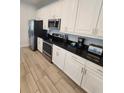Modern kitchen features white cabinets, black countertops, stainless steel appliances, and tiled floor at 7623 Wilmington Loop, Kissimmee, FL 34747